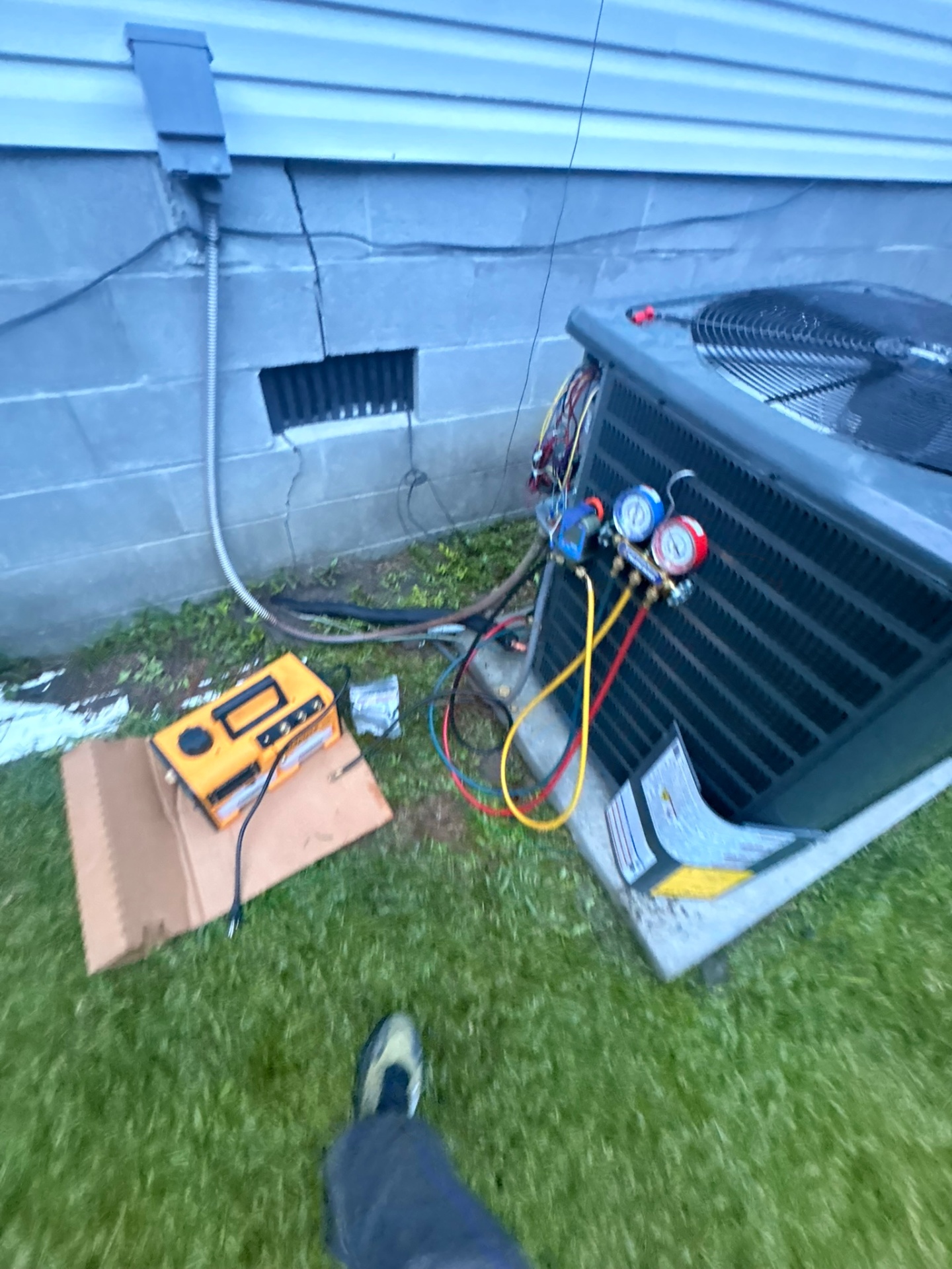 Perfect Temp technician servicing an outdoor AC unit with gauges and tools during a service call